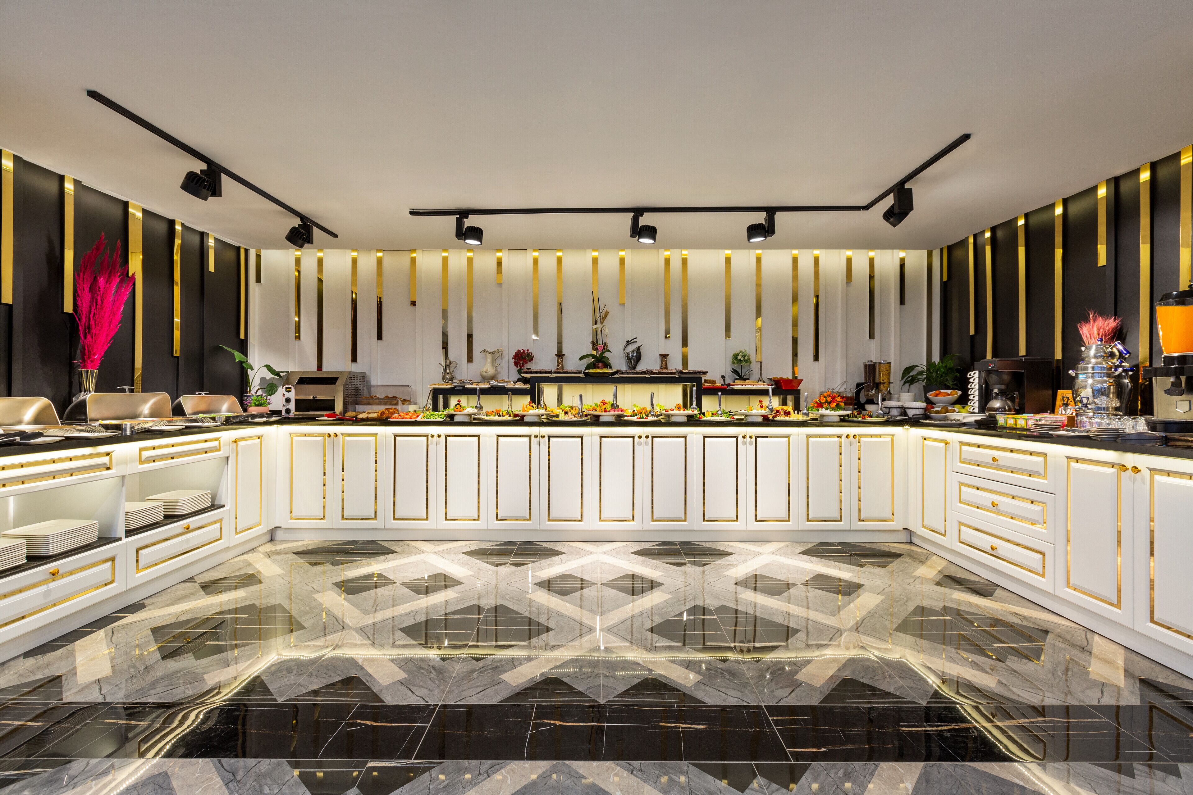 A modern kitchen with white cabinetry, black and gold accents, and a geometric marble floor.