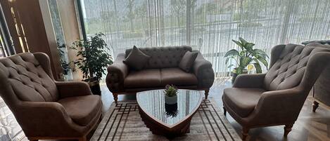 A modern living room with a brown leather sofa, two armchairs, and a glass coffee table.
