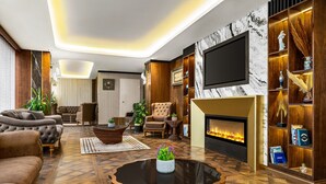 A modern living room with a fireplace, comfortable seating, and a TV. - Trademark Collection By Wyndham Operla İstanbul Airport Hotels (Arnavutköy)