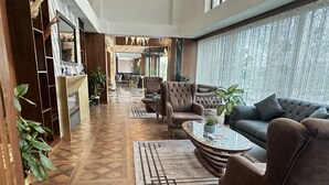 A modern living room with a herringbone floor pattern, a glass coffee table, and a grey sofa. - Trademark Collection By Wyndham Operla İstanbul Airport Hotels (Arnavutköy)