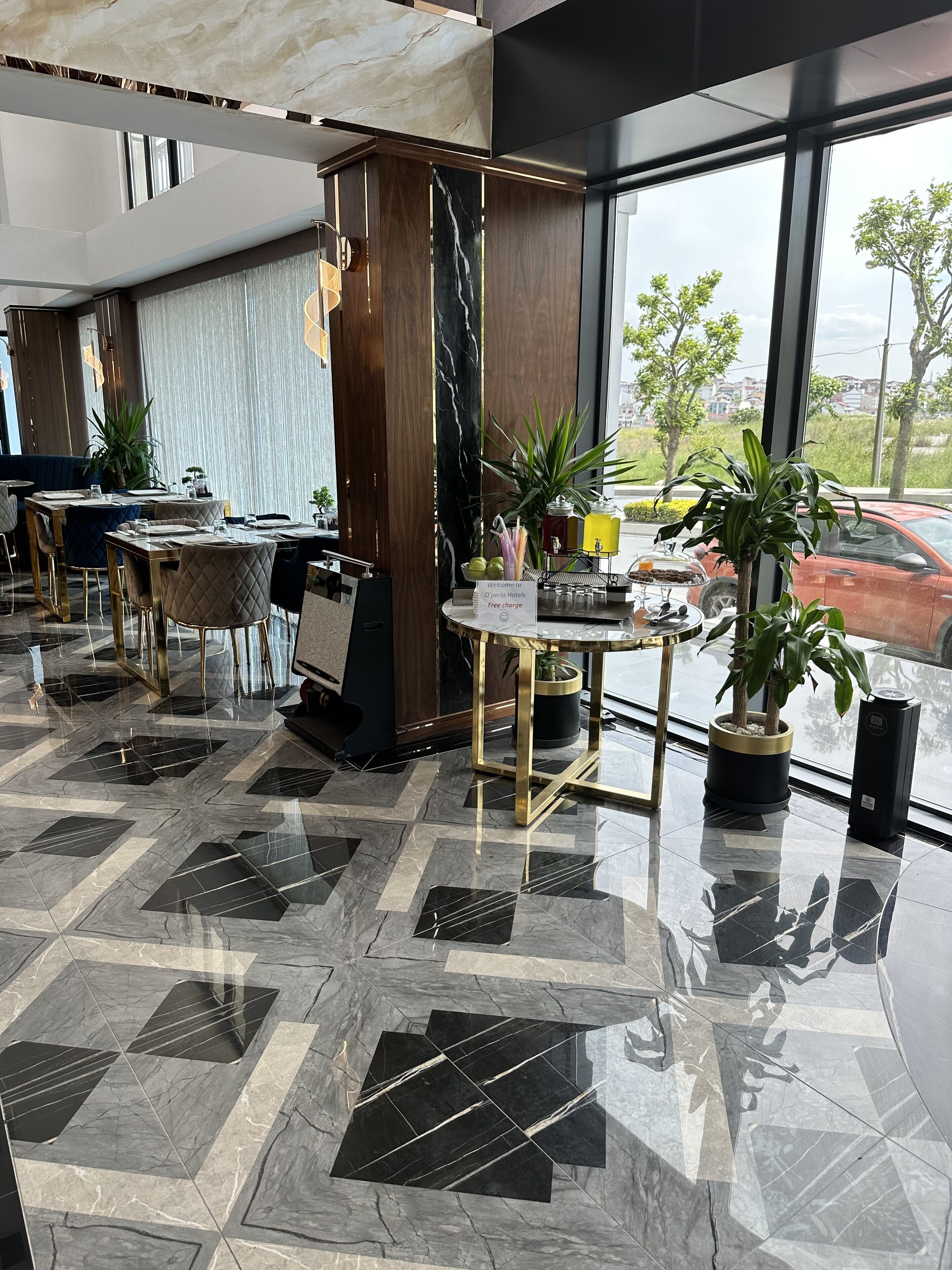 A modern hotel lobby with marble flooring, a reception desk, and potted plants.