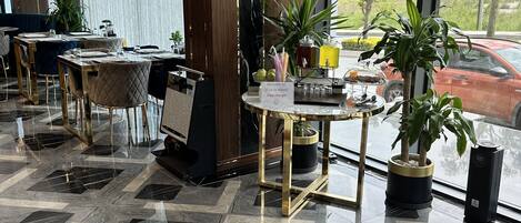 A modern hotel lobby with marble flooring, a reception desk, and potted plants.