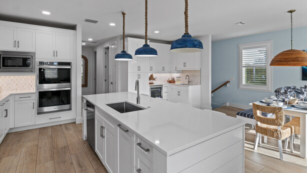 Una cocina moderna con armarios blancos, electrodomésticos de acero inoxidable y una isla central.