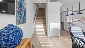 Una cocina moderna con armarios blancos, una escalera de madera y lámparas colgantes.