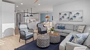 Una sala de estar moderna con un sofá gris, otomanas estampadas y sillones de mimbre.