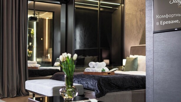 A modern hotel room with a bed, bedside table, and a large mirror. - Stay Inn  on Buzand Str. 97 (Yerevan)