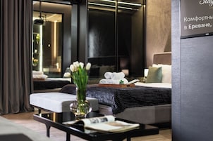 Een moderne hotelkamer met een bed, nachtkastje en een grote spiegel.