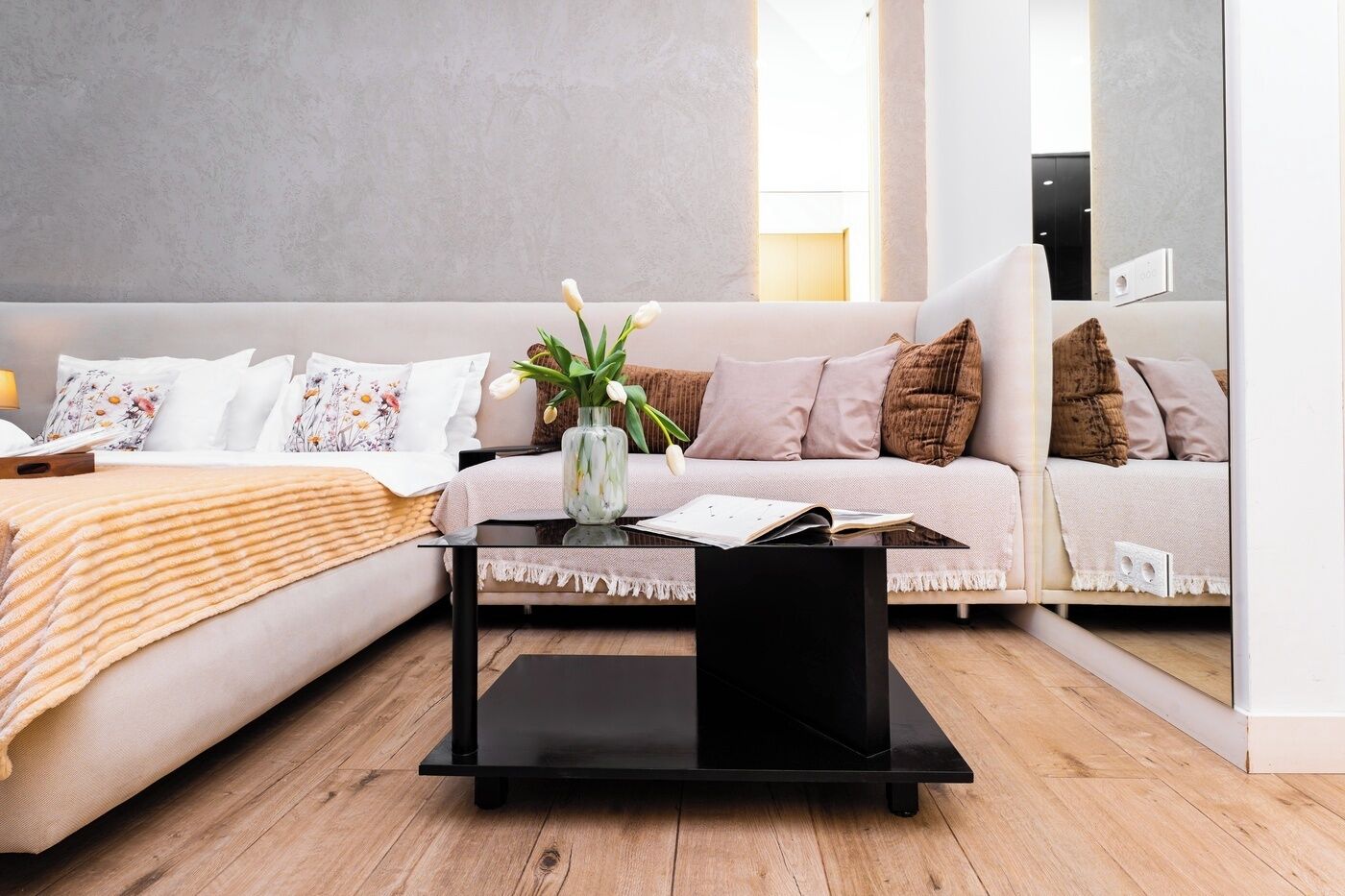 A modern living room with a sofa, a coffee table, and a vase with flowers.