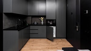 A modern kitchen with dark cabinetry, a black countertop, and a wooden floor. - Stay Inn  on Buzand Str. 97 (Yerevan)