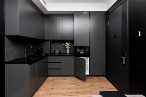Een moderne keuken met donkere kastjes, een zwart aanrecht en een houten vloer.