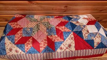 A quilted blanket with a geometric pattern, placed on a wooden bench.