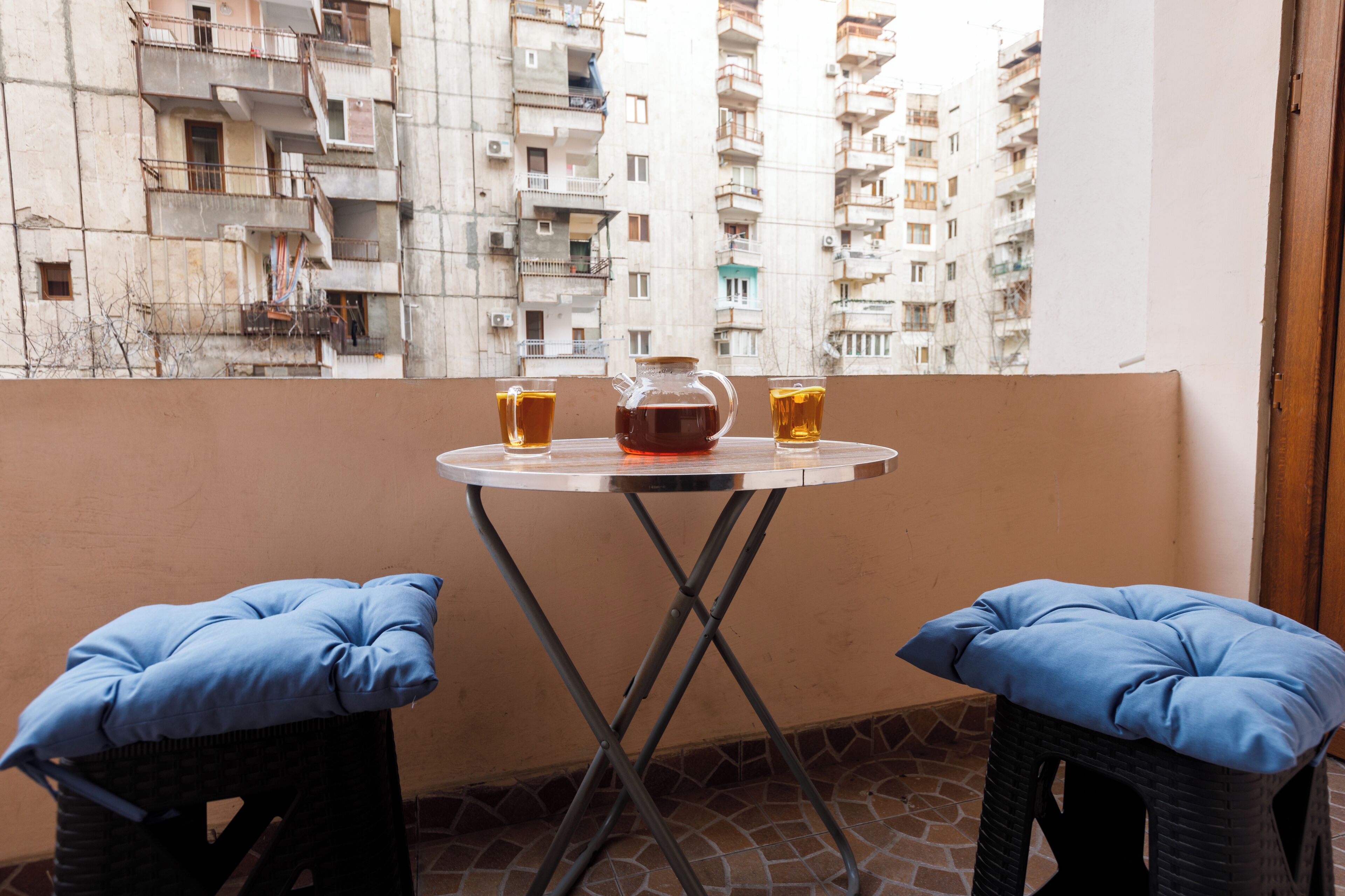 A balcony with a table, two stools, and a pitcher of beer.