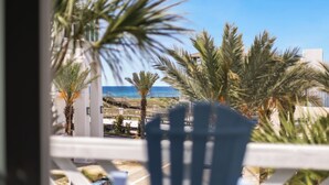 A balcony with a view of the ocean, palm trees, and a building in the background. - Inlet Beach + Gulf View, Pet Friendly & Bikes (Inlet Beach)