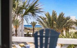 A balcony with a view of the ocean, palm trees, and a building in the background. - Inlet Beach + Gulf View, Pet Friendly & Bikes (Inlet Beach)