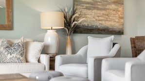 A living room with a sofa, armchair, ottoman, lamp, vase, and a painting on the wall. - Inlet Beach + Gulf View, Pet Friendly & Bikes (Inlet Beach)