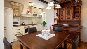 Cucina con mobili bianchi, un tavolo da pranzo in legno e un lampadario.