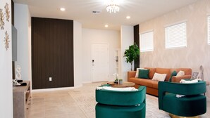A modern living room with a sofa, two green ottomans, a coffee table, and a potted plant. - Stylish family friendly, 5 suites near Disney! (Davenport)