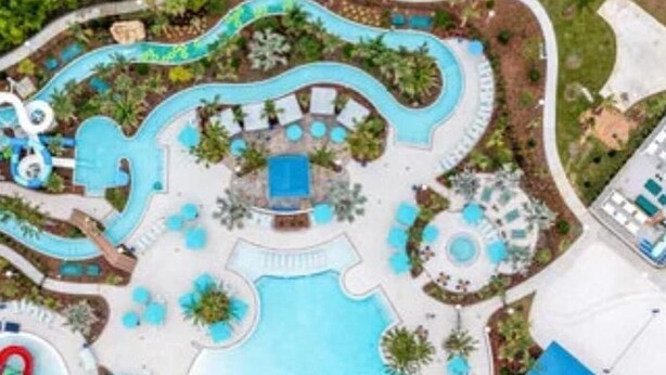 An aerial view of a resort with multiple swimming pools, lounge areas, and a large building structure. - Stylish family friendly, 5 suites near Disney! (Davenport)