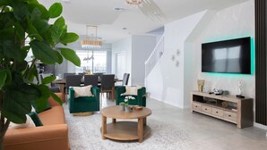 A modern living room with a sofa, coffee table, and TV. There is a staircase leading to another level. - Stylish family friendly, 5 suites near Disney! (Davenport)