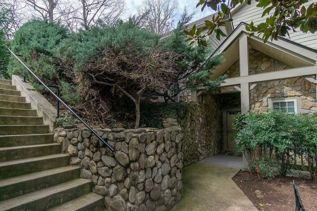 A stone staircase leading to a house with a stone wall and a small garden area.