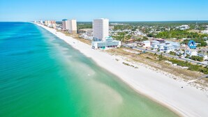A coastal cityscape with a beach, high-rise buildings, and a clear blue sky.
