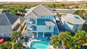 A large house with a swimming pool, located near a beach with a clear view of the ocean.