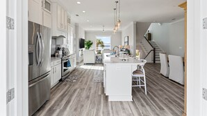 A modern kitchen with stainless steel appliances, a central island, and a view to the living area.