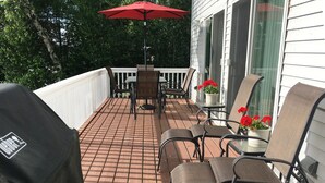 En overdækket terrasse med bord og stole, grill og krukker med planter.