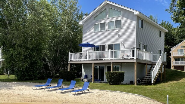 Et toetagers hus med balkon, sandstrand og blå liggestole.