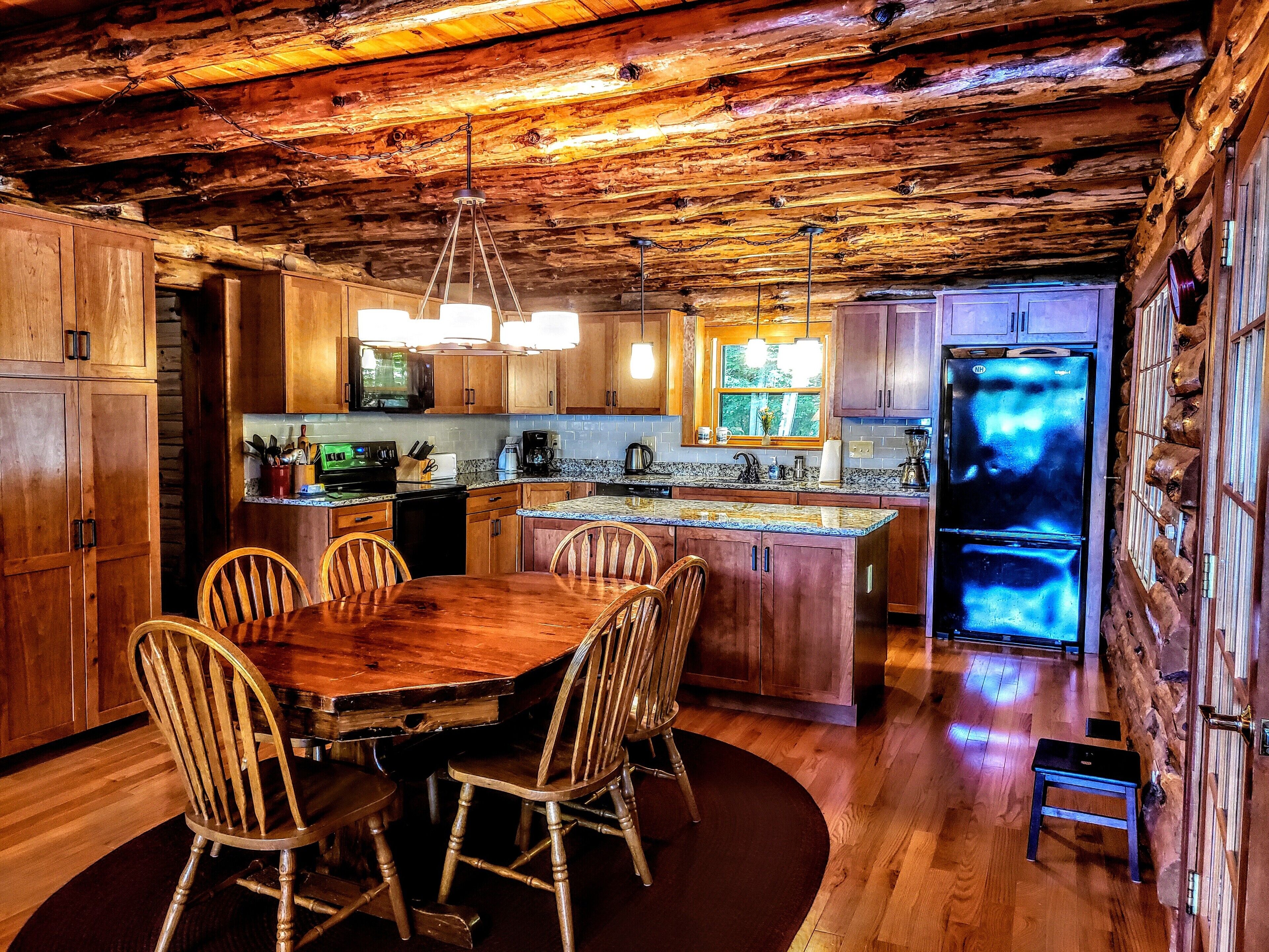 A rustic kitchen with wooden cabinets, a central island, and a refrigerator.