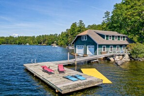 A house with a dock extending into a lake, surrounded by trees.