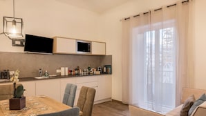 A modern kitchen with built-in appliances, a dining area with a table and chairs, and a large window with curtains. - Apartment "Annabel" with Mountain View, French Balcony & Wi-Fi (Bolzano)