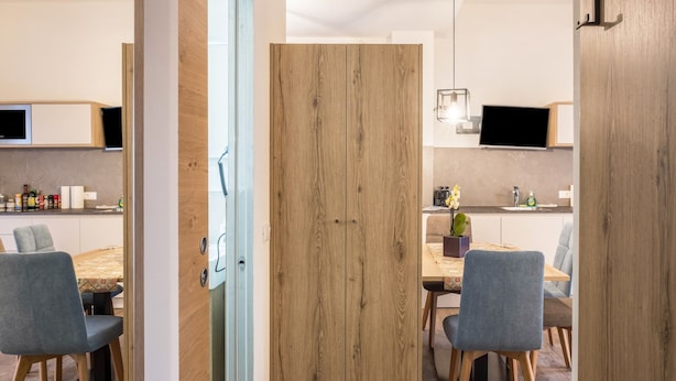 A modern kitchen with wooden cabinets, a dining table, and chairs. - Apartment "Annabel" with Mountain View, French Balcony & Wi-Fi (Bolzano)