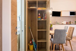 Une cuisine avec des meubles de rangement en bois, une table à manger avec des chaises et un téléviseur fixé au-dessus du comptoir.