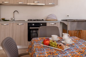 A kitchen with a table set for breakfast, including a croissant, apple, and grapes.