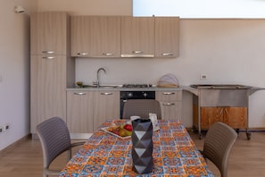 A compact kitchen with wooden cabinets, a gas stove, and a dining table with chairs.