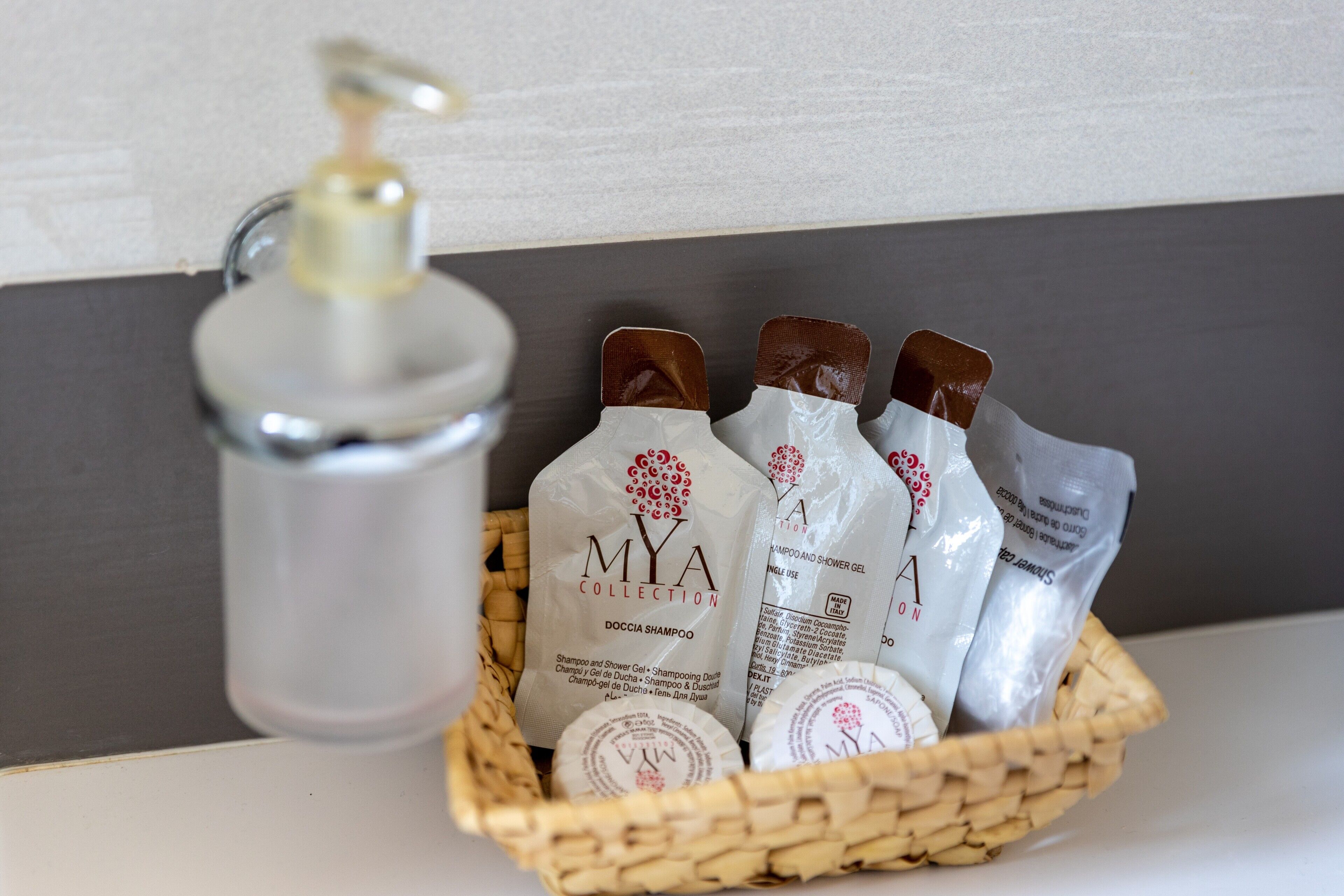 A bathroom with a soap dispenser, a basket containing shampoo bottles, and a bottle of conditioner.
