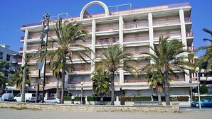 A multi-story hotel with balconies, palm trees, and a clear blue sky. - Apartment Ancora by Interhome (Salou)