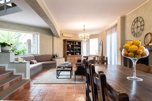 Un salon moderne comprenant un canapé, une table à manger, des chaises, un lustre et une bibliothèque.