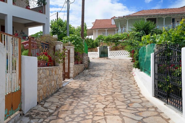 Un chemin pavé de pierres mène à un bâtiment à l’extérieur blanc et au toit recouvert de tuiles rouges.