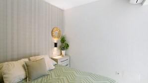A bedroom with a bed, pillows, a bedside table with a lamp, a wall-mounted mirror, and a potted plant. - Vacation 'Dreaming Penthouse Mogan' with Mountain View, Wi-Fi and Air Conditioning (Mogán)
