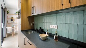 A modern kitchen with wooden cabinets, a black countertop, a sink, and a tiled backsplash. - Vacation 'Dreaming Penthouse Mogan' with Mountain View, Wi-Fi and Air Conditioning (Mogán)