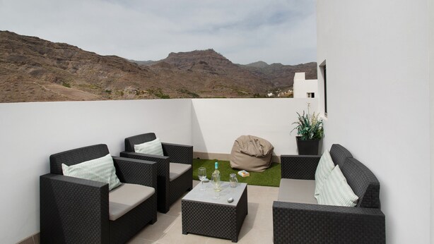 A balcony with outdoor furniture, a small table, and a potted plant. - Vacation 'Dreaming Penthouse Mogan' with Mountain View, Wi-Fi and Air Conditioning (Mogán)