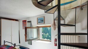 A room with a bed, a window with a view of greenery, a wooden spiral staircase, and a red lantern. - Holiday Home "Seroa 1" with Sea View, Shared Terrace and Wi-Fi (Vernazza SP)