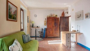 A room with a green sofa, a wooden cabinet, a small table, and a clock on the wall. - Holiday Home "Seroa 1" with Sea View, Shared Terrace and Wi-Fi (Vernazza SP)