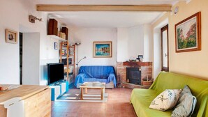 A living room with a TV, sofa, fireplace, and a green couch. - Holiday Home "Seroa 1" with Sea View, Shared Terrace and Wi-Fi (Vernazza SP)
