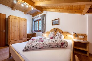 Quarto de dormir com cama, guarda-roupa, janela e um quadro na parede.