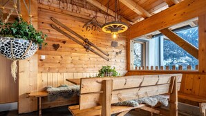 Een houten cabin met een bankje, hangplanten en een rustieke lamp.