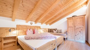 Een slaapkamer met houten meubels, waaronder een bed, nachtkastje, dressoir en een bank.