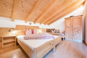 A wooden bedroom with a bed, a nightstand, a dresser, and a sofa.